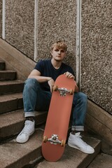 Blond skate sitting on steps with dulled orange skateboard © Rawpixel.com
