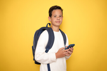 Teenager boy wearing headphones and using smartphone over isolated background