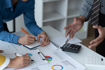 close-up hands image, Professional Asian male and female financial consultant or analyst working with them team, brainstorming and analyzing financial data on the report together in the office