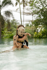 Happy mother and baby girl  in swimming pool, smile and have fun, summer vacation concept