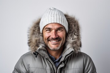Portrait of a satisfied man in his 40s dressed in a warm ski hat in white background