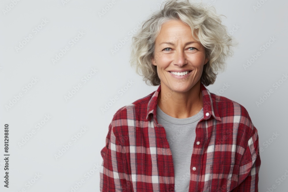 Wall mural Portrait of a happy woman in her 60s wearing a comfy flannel shirt in front of white background