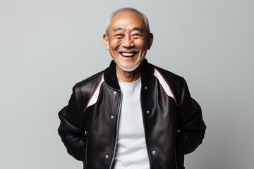 Obraz premium Portrait of a grinning asian man in his 60s sporting a stylish varsity jacket isolated on white background