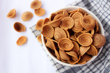 Kue kuping gajah or elephant ear cakes are a traditional Indonesian snack served in a bowl on an isolated background.