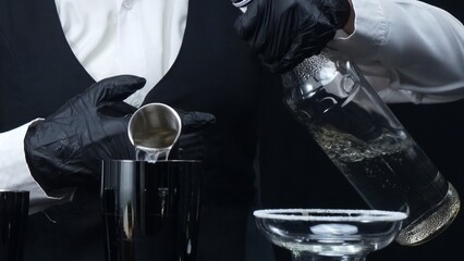 Professional bartender pouring fresh margarita with salted garnish glass. Macrography of skilled...