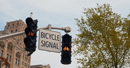 Bicycle sign and dedicated bike traffic light against a city backdrop promote safe cycling lanes....