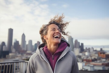 Portrait of a joyful woman in her 40s wearing a zip-up fleece hoodie over vibrant city skyline