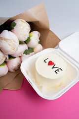 Bento cake with the inscription "Love and Hearts" and a bouquet of flowers. A cute dessert gift for any occasion for a loved one. Greeting card. Love and sweets concept