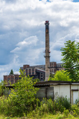 Fototapeta na wymiar An old building and chimney at a coal mine in Gliwice, Poland. They make an oddly satisfying mix of colours along with the nature below and sky above.