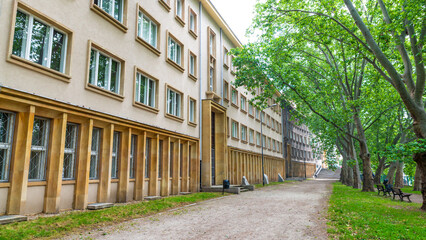 Green trees along the Oder River surrounds the path next to the majestic building housing the...