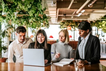 Diverse business people brainstorming using laptop