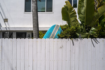 Surfboard Behind White Picket Fence