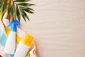 Beach setup featuring sun protection spray and lotion against a sandy backdrop, adorned with a...