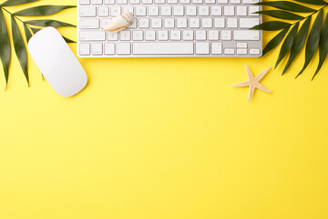 Remote work setup with top view of keyboard and mouse on yellow background with palm leaves and...