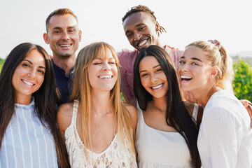 Group of multiracial people smiling on camera during summer time outdoor - Young friends hugging...