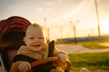 Portrait of a cute toddler girl in a stroller in the park