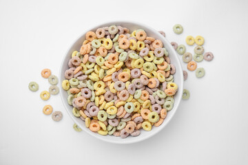 Tasty cereal rings in bowl on white table, top view