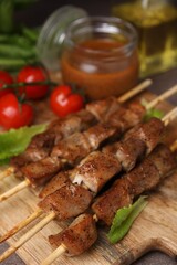 Tasty cooked marinated meat served with sauce and tomatoes on table, closeup