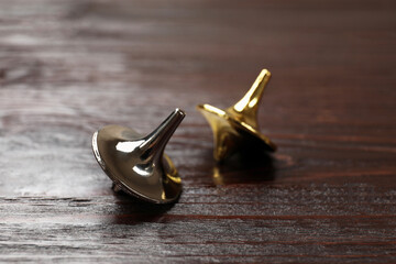 Two metal spinning tops on wooden table, closeup