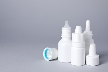 Bottles of medical drops on gray background, space for text