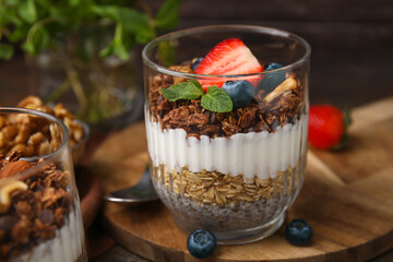 Tasty granola with berries, yogurt and chia seeds in glass on table, closeup