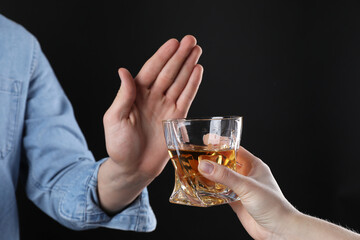 Alcohol addiction. Man refusing glass of whiskey on dark background, closeup
