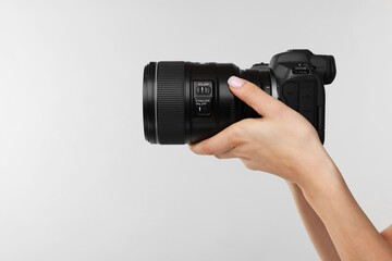 Photographer with camera on light grey background, closeup. Space for text