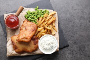 Tasty fish, chips, sauces and peas on grey table, top view. Space for text