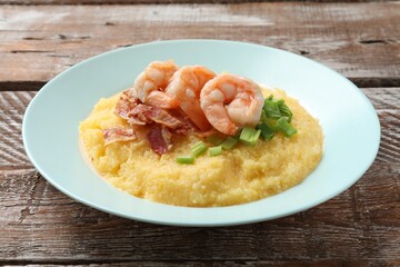 Plate with fresh tasty shrimps, bacon, grits and green onion on wooden table
