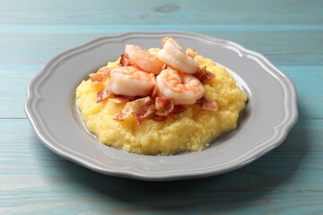 Plate with fresh tasty shrimps, bacon and grits on light blue wooden table