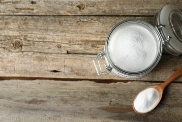 Baking soda in jar and spoon on wooden table, top view. Space for text