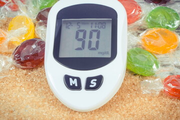 Glucose meter with sugar level, candies and cookies. Healthy nutrition and reduction eating sweets during diabetes
