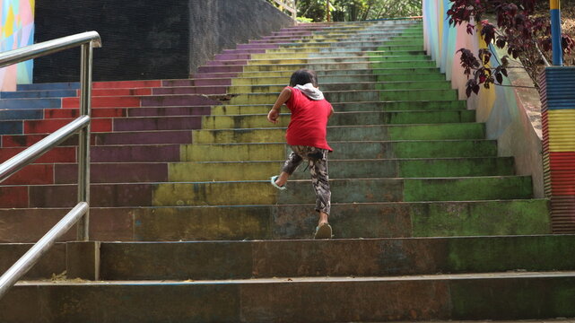 boys playing in the park, running up the colorful stairs