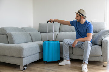boy with hat on looking and holding his suitcase before going on vacation