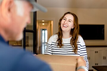Brunette woman receiving package box from delivery man, online shopping image