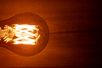 A60 E27 Edison light bulb, also known as filament light bulb on wooden background.