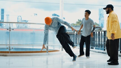 Hipster perform break dance while friend encourage him at mall. Diverse or multicultural street...