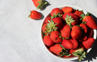 Strawberries in a white bowl on a light background, top view