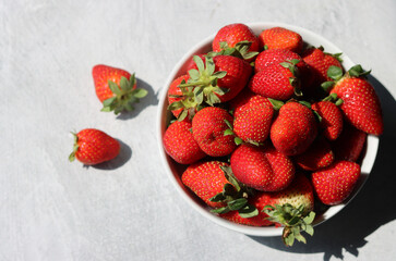 Strawberries in a white bowl on a light background, top view