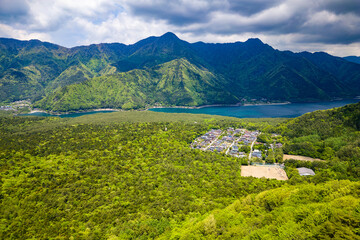 Fototapeta premium Drone view of lush forest, rugged mountains and a small lake