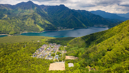 Aerial view of lush green forest surrounding a volcanic lake (Lake Saiko, Yamanashi, Japan)