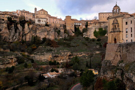View of the gorge, overhanging cliffs and the building of the Antiguo Convento de San Pablo against a dramatic sky in the city of Cuenca, near Madrid, Spain