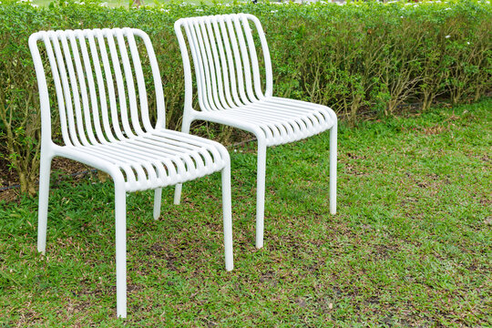 Two plastic white chairs in the garden backyard, garden ladder back chairs outside the house