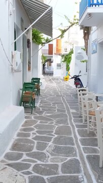 Walking with steadycam in picturesque narrow street with traditional whitewashed houses with blooming bougainvillea flowers of Naousa town in famous tourist attraction Paros island, Greece