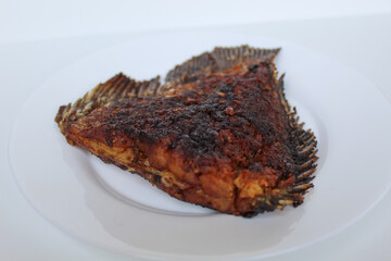 Grilled gourami fish tail, on a white plate, isolated on white background