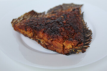 Grilled gourami fish tail, on a white plate, isolated on white background