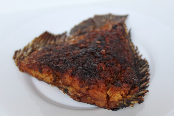 Grilled gourami fish tail, on a white plate, isolated on white background