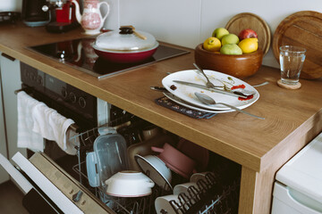 used dirty dishes on wooden kitchen countertop, with built-in dishwasher