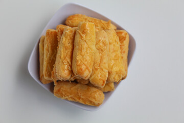 Kaasstengels or Kastengel, is Dutch influenced Indonesian cheese cookies in the form of sticks. Isolated in white background, flat lay or top view