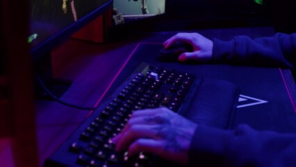 Gamer typing on backlight keyboard close-up, man playing video game in blue neon light . Male hands pushing buttons on computer mouse. having a stream, cyberspace.